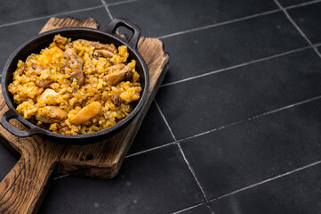 Pilaf with beef and lamb meat, vegetables in a skillet. black background. top view