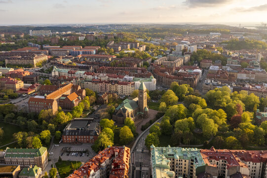 Aerial view of Tradgardsforeningen park's verdant canopy surrounds the imposing architecture of the church, bathed in the warm glow of the setting sun, Gothenburg, Vastra Gotaland, Sweden.