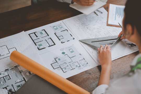 Architects working on construction project blueprints using ruler and compass