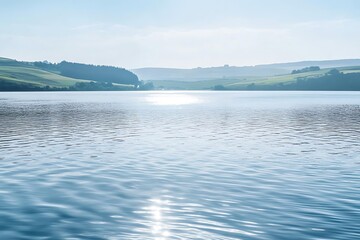 Wide shimmering lake with ripples in the breeze and soft hills fading in the background 