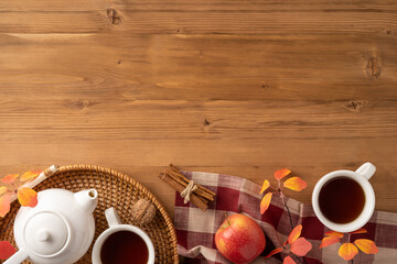 Top view of a warm autumn scene featuring tea, apples, and fall decorations