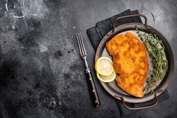 German Wiener schnitzel steak, breaded pork fillet meat. black background. top view