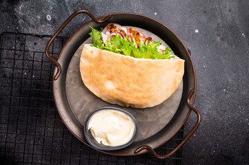 Gyros with grilled chicken meat, salad, tomato, onion, tzatziki in pita bread. black background....