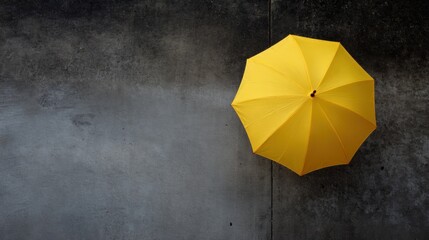 Single yellow umbrella lying on a dark grey concrete surface. the umbrella is open, with its handle facing towards the right side of the image.