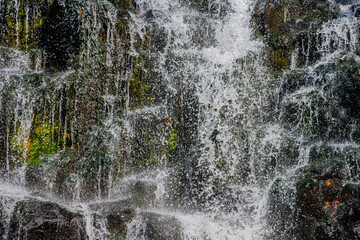 岩肌を滑り落ちる水と飛び散る水滴の滝クローズアップ