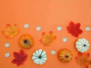 A flat Halloween composition with pumpkins, leaves on a pastel orange background.
