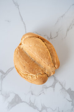 Round loaf of spanish candeal bread on marble surface