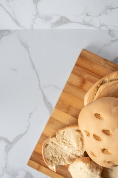 Traditional Spanish candeal bread loafs resting on wooden cutting board on marble surface
