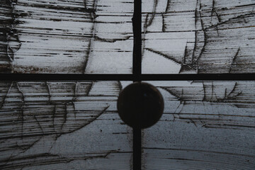 Weathered translucent roof seen from below, with visible dirt streaks, cracks, and a dark metal...