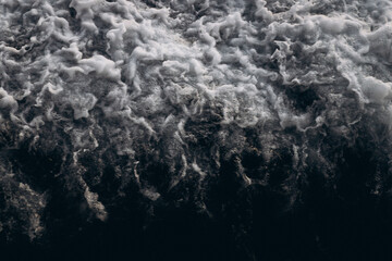 A close-up, abstract view of churning sea foam and waves, showing the dynamic texture and movement...