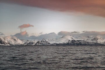 A panoramic landscape featuring a vast, dark sea under a dramatic sky with a large, sweeping cloud...