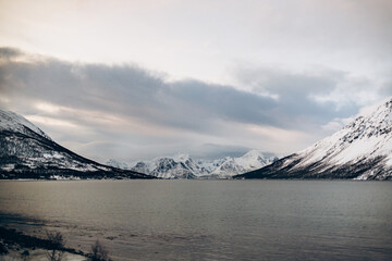 A peaceful view of a calm sea with gently rippling waves, set against a backdrop of snow-covered...