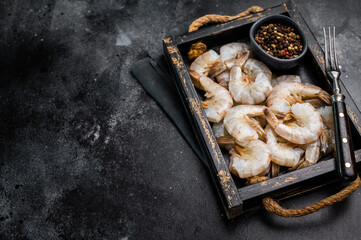 Fresh Raw headless tiger shrimps prawns in a tray. Top view. Black background
