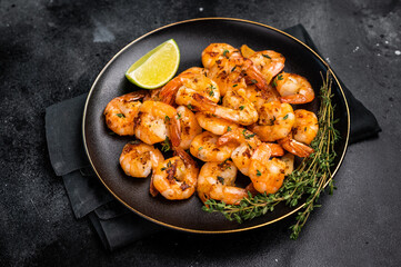 Grilled spicy Shrimps Prawns with garlic and lime in a plate. Black background. Top view