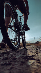 Young man riding bike on gravel road at sunset. Cyclists Going Uphill at Sunset