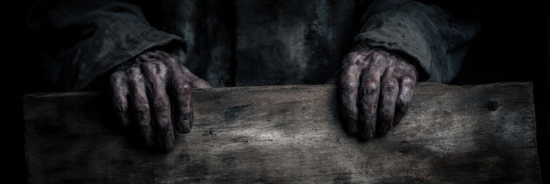 Eerie hands gripping old wooden panel in dim light