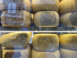 Close-up of artisanal cheeses arranged on wooden shelves. Food and culinary concept
