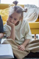 Curious little child girl reading book at home, indoor portrait