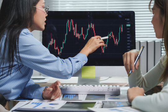 Businesswomen analyzing financial charts on computer screen - Powered by Adobe