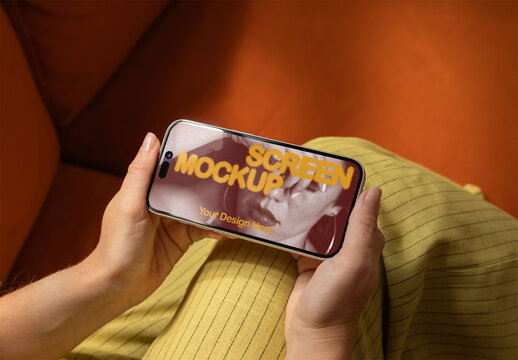 Mockup of Handheld horizontal Smartphone on a Cozy Couch