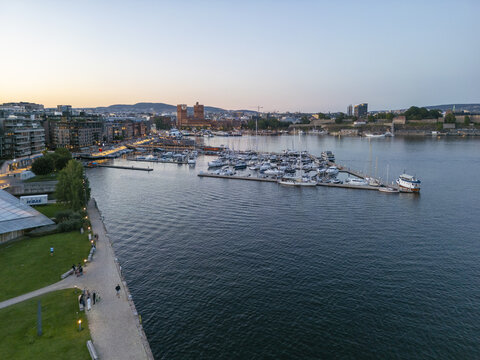 Aerial view of the deep blue water reflecting the twilight sky, boats docked near the Aker Brygge waterfront and Oslo City Hall, Oslo, Oslo, Norway.