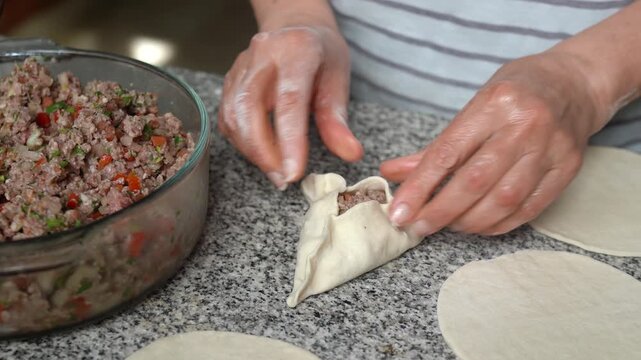Close-up of woman's hands making meat fatayers also known as Middle Eastern savory hand pies