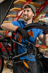 Male bicycle technician wearing gloves repairing disc brake system on mountain bike
