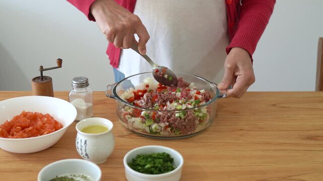 Woman mixing the filling to prepare Lebanese meat fatayer also known as Middle Eastern savory hand pies