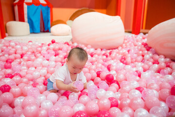 Little baby having fun inside pink ball pit