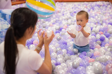 Mother playing with baby in purple ball pit