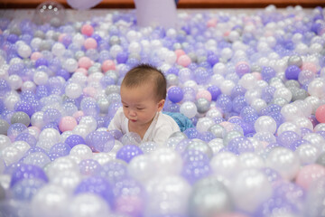 Little baby having fun in purple ball pit