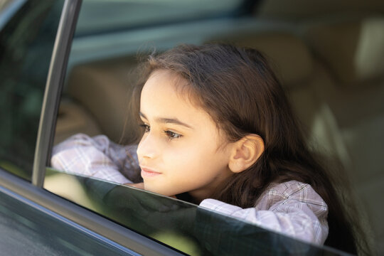 Headshot of a cute school-aged girl looking out of the car window - Powered by Adobe