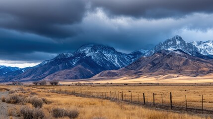 Fototapeta premium Majestic mountain landscape under stormy skies, showcasing vast fields and distant fences in nature's beauty
