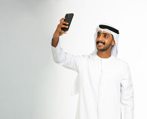 Portrait of an emirati man on a white background taking selfie.