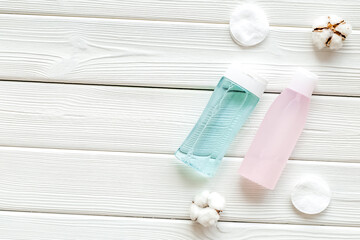 facial tonic, lotion and cotton pads for face care on white wooden background top view mock up