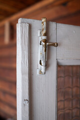 Rustic barn door latch. Latch on a wooden door with a glass panel. Antique latch. Latch on a wooden...