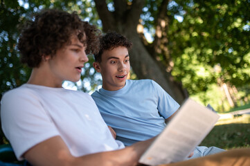 Two teens in the park preparing for the lessons and reading a book