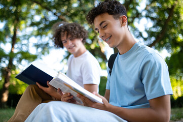 Two teens in the park preparing for the lessons and reading a book