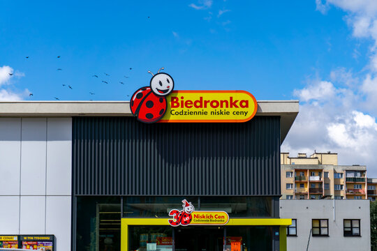 Biedronka store logo with slogan &ldquo;Everyday low prices&rdquo; on building facade with apartment blocks in background.