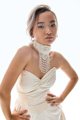 Young Asian bride in an elegant white dress, exuding timeless grace in a studio