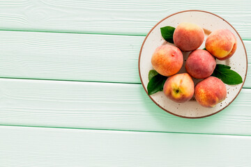 Summer fruits. Ripe red peaches on plate on green wooden table top-down copy space