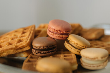colorful macaroons and Belgian waffles on a wooden table