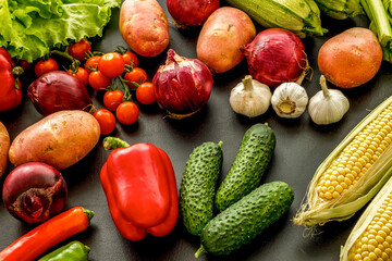 Fresh vegetables still life. Potato, cucumber, beet carrot, greenery on black background
