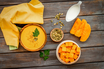 Pumpkin soup on wooden table top view. Ingredients in bowls