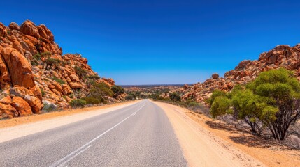 Scenic view of a winding road through rocky terrain under a clear blue sky, showcasing nature's beauty
