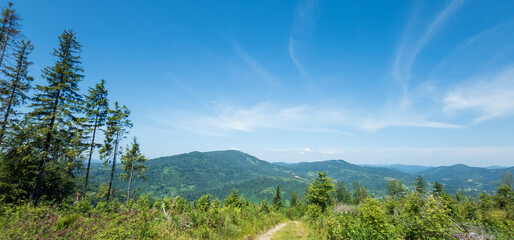 A sweeping view of lush mountains under a bright blue sky with wispy clouds, perfect for travel...