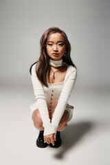 Young Asian woman showcases trendy style in a chic studio setting