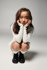 Stylish young asian woman poses thoughtfully in a minimalist studio setting