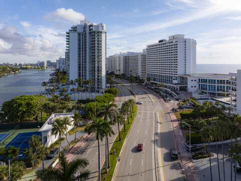 Aerial view of Collins Avenue lined with palm trees and modern buildings contrasting against the blue ocean, Miami Beach, Florida, United States.