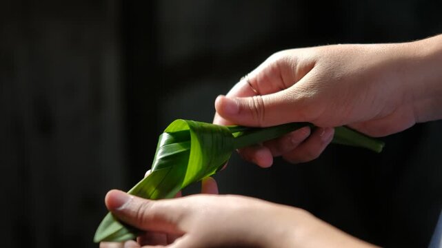 Woman folding pandan leaves